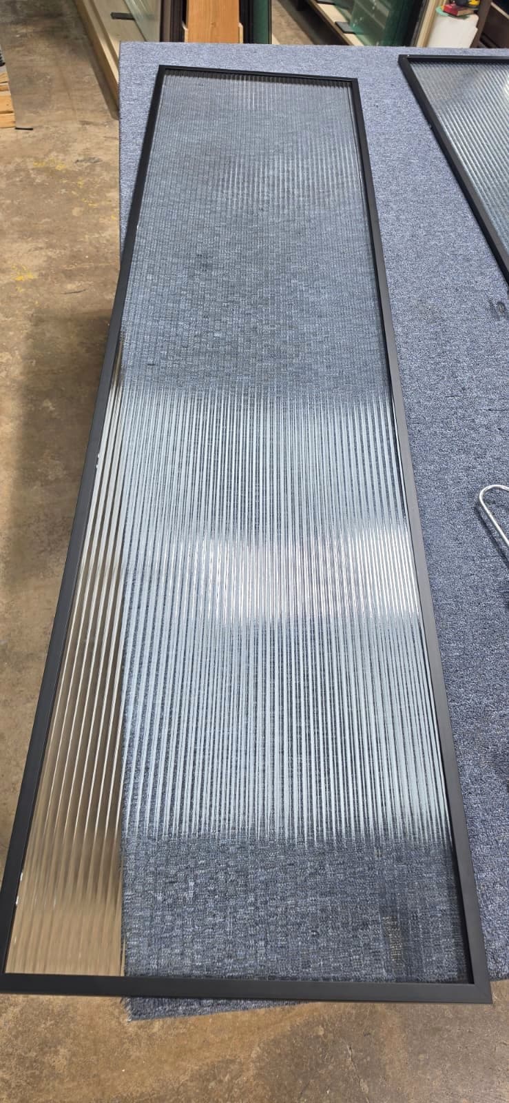 Black aluminum frame door with tempered fluted glass on the workbench