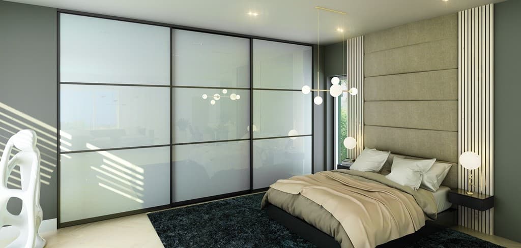 Frosted glass sliding closet doors with black frames in a bedroom
